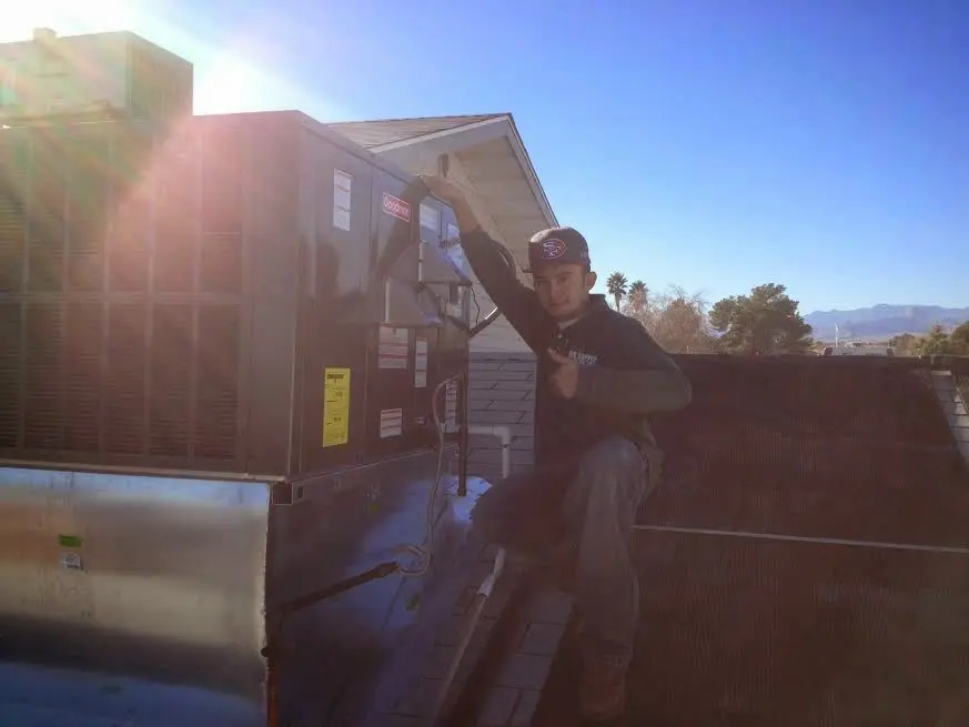 HVAC technician performing Air Duct Cleaning on a rooftop unit in Lansing
